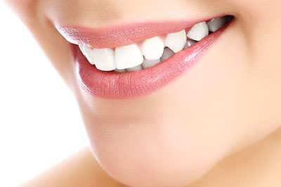 A close-up of a person s face with a focus on their teeth, which are being highlighted by a bright smile