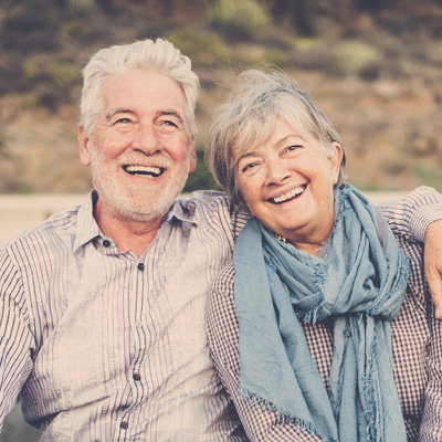 A woman with a radiant smile leaning on her arm with a warm expression