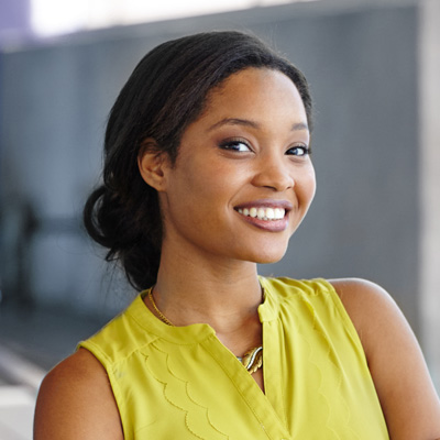 A young woman with a warm smile posing confidently against a wall